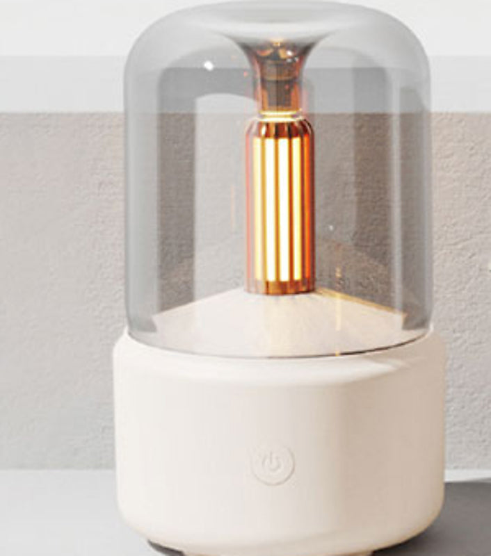 Close-up of the candlelight night-light diffuser, its flame-effect bulb glowing warm amber under the glass dome