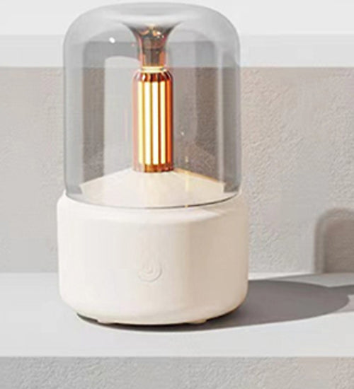 Cream flame-effect aroma diffuser glowing like candlelight on a shelf against a soft neutral wall