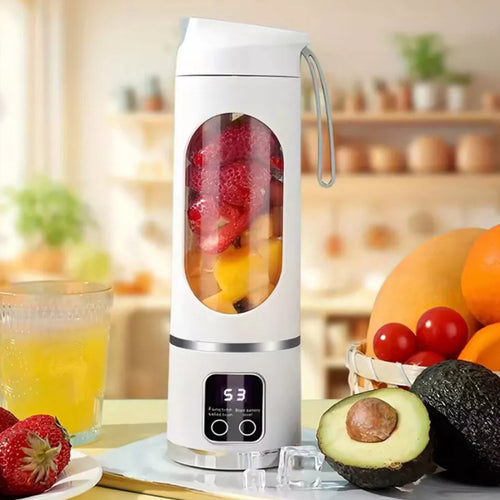 White personal blender for smoothies on a kitchen counter beside a glass of juice and a bowl of fresh fruit