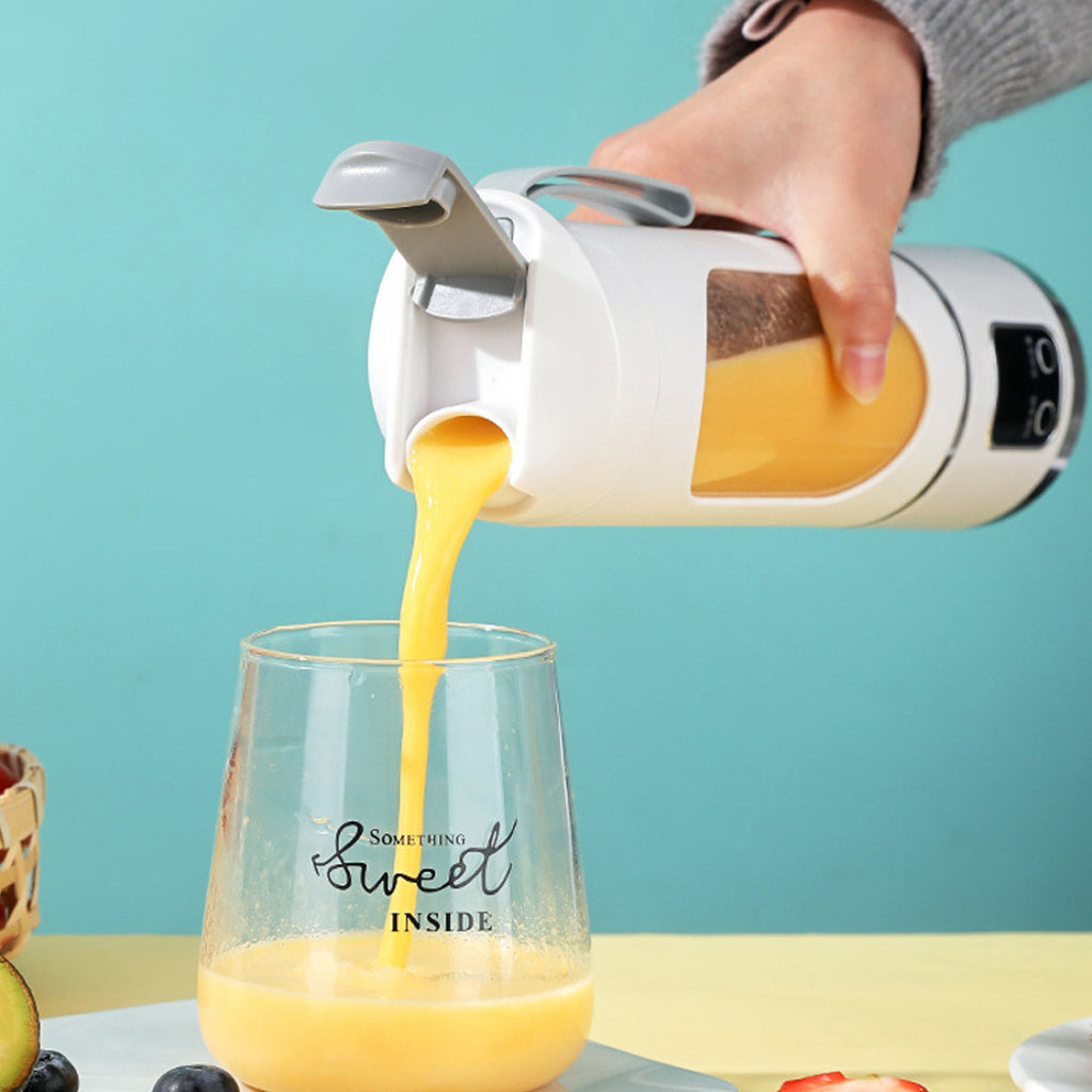 A hand pouring a freshly blended smoothie from the single-serve blender into a clear glass
