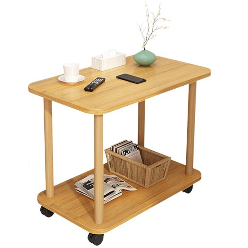 Two-tier side table on wheels seen from three-quarters against a plain background, with a cup and saucer, a tissue box, a vase, a remote control and a phone on the top and a basket of magazines on the shelf below. The items shown are not included.